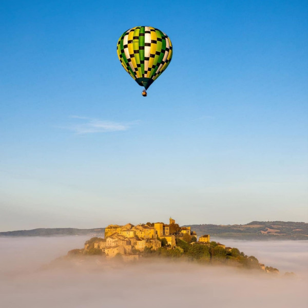 Montgolfière sur le village médiéval de Cordes sur Ciel dans un décor de brume.
